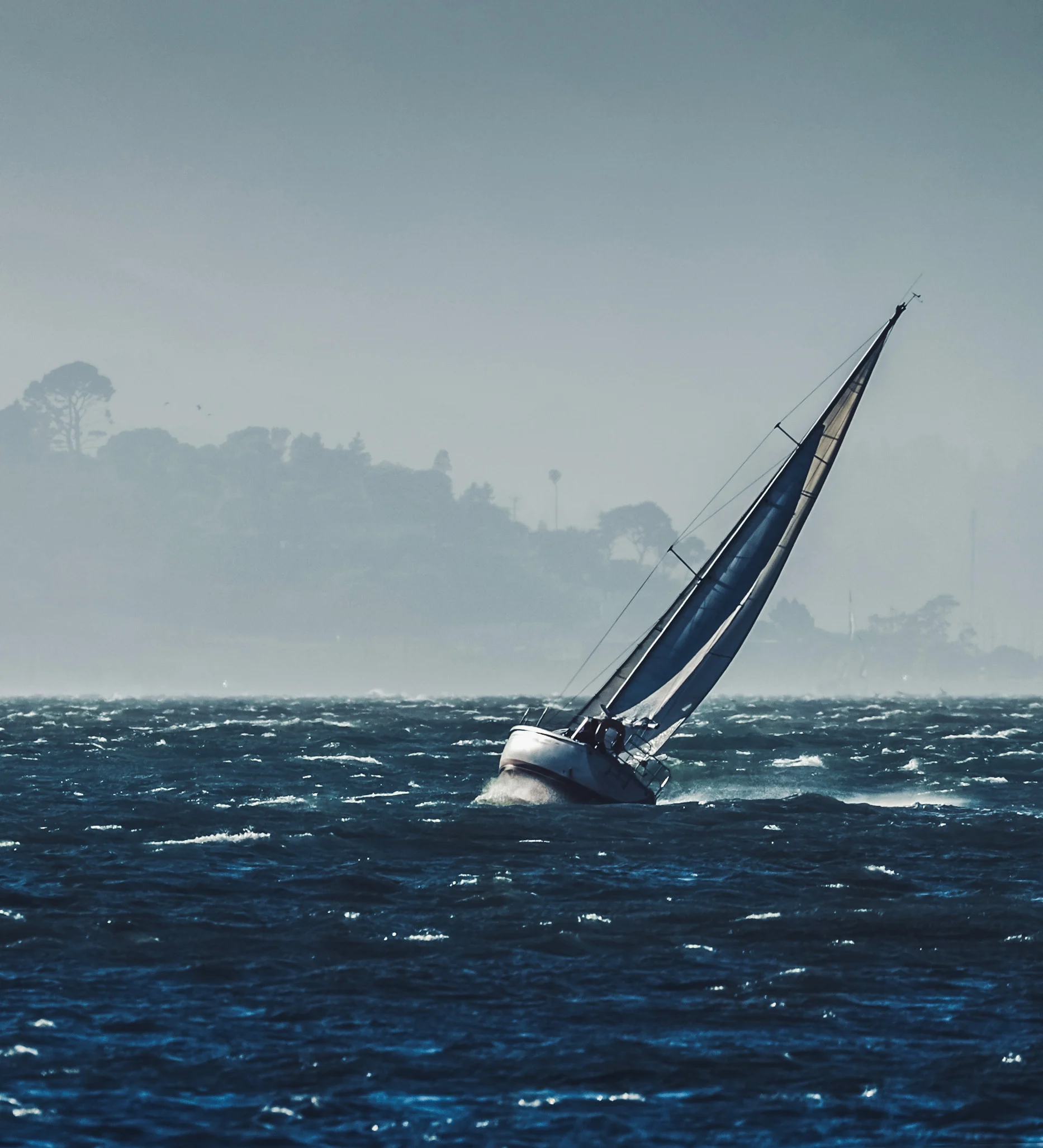 Sailboat moving across open water toward the horizon.