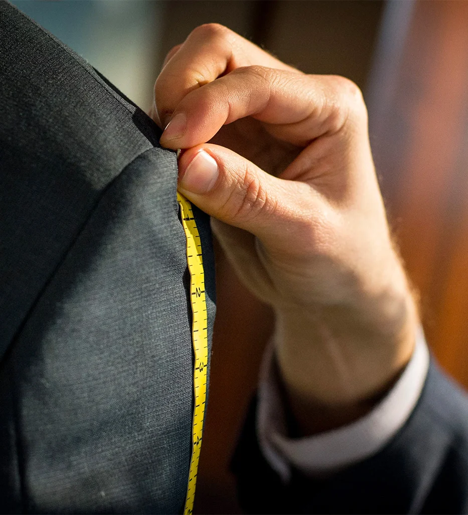 Tailor's hand measuring a dark suit shoulder